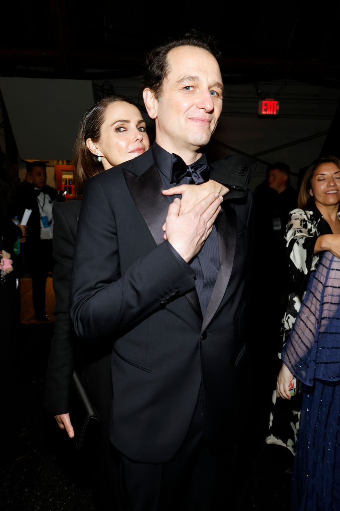 woman standing behind man with arms wrapped around